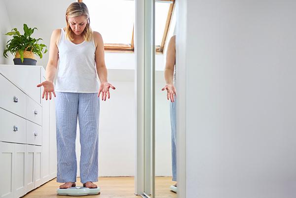 a woman standing on a scale in a room with a mirror