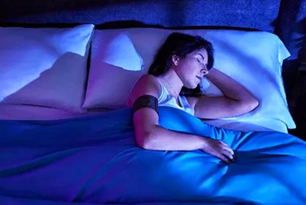 a woman laying in bed wearing a garmin watch