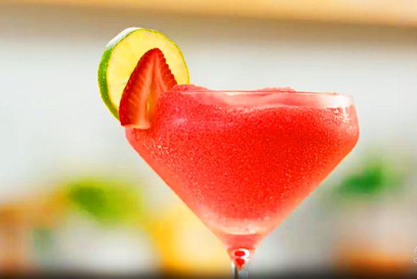 a close up of a slushy drink with a slice of lime and a strawberry