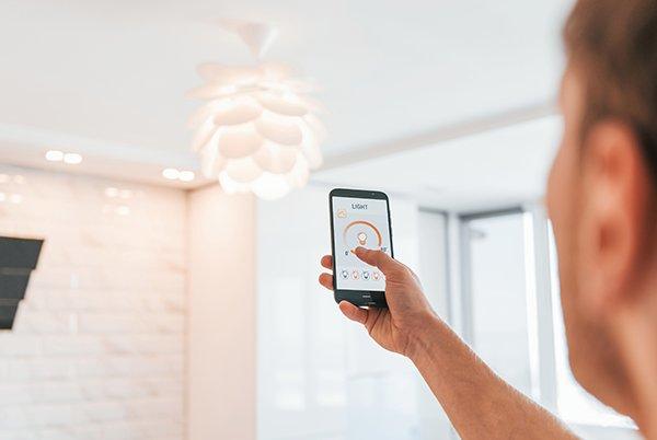 a man holding a smart phone in his hand while looking at smart lighting