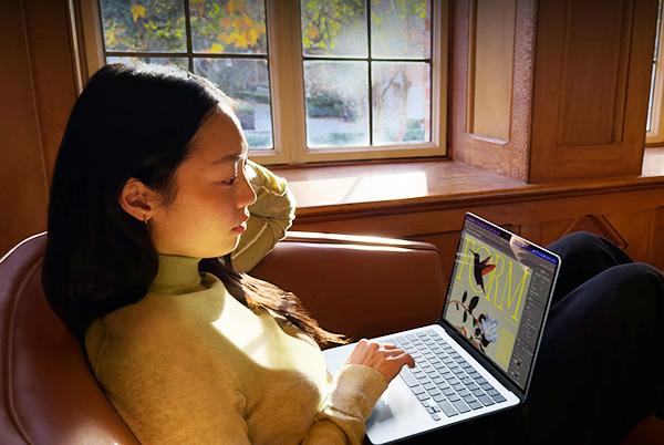 a woman sitting in a chair with a macbook