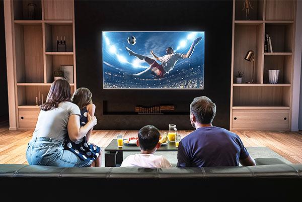 a family watching a football game on a large flat screen tv