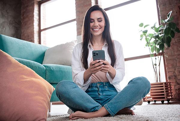 a woman sitting on the floor with an iphone in her hand