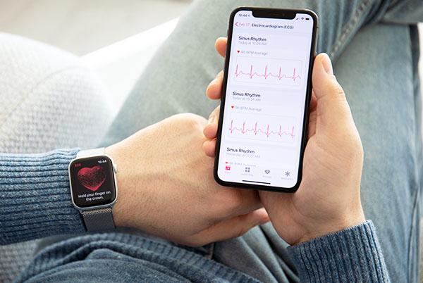 a person holding an Apple Watch and iphone with a heartbeat monitor onscreen