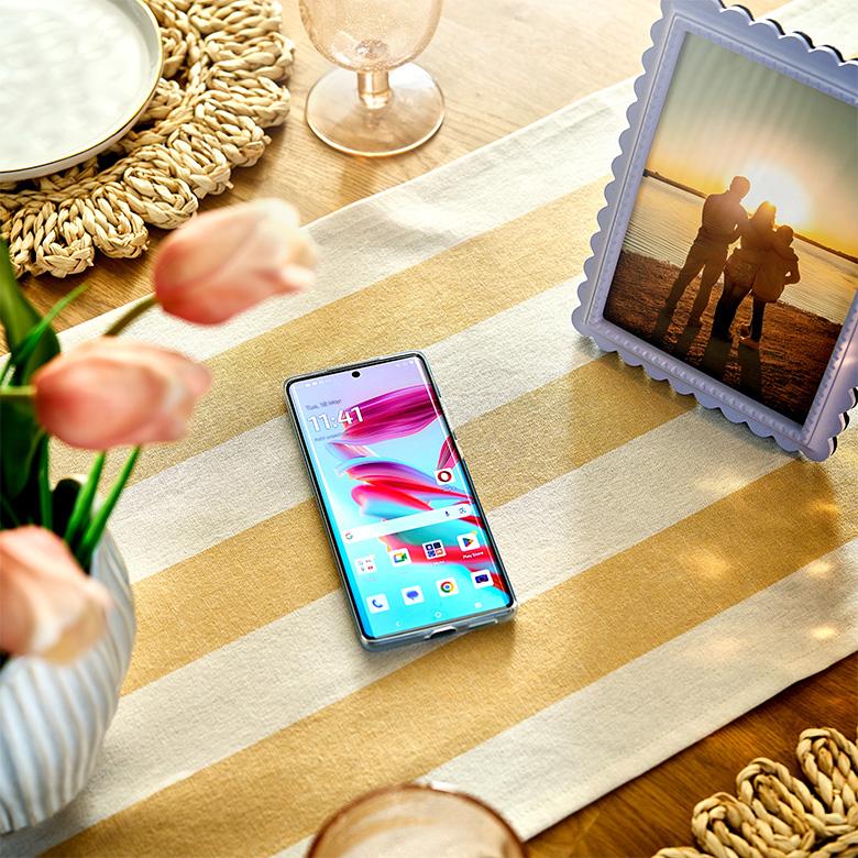 a motorola moto g85 phone sitting on a table next to a picture of a couple