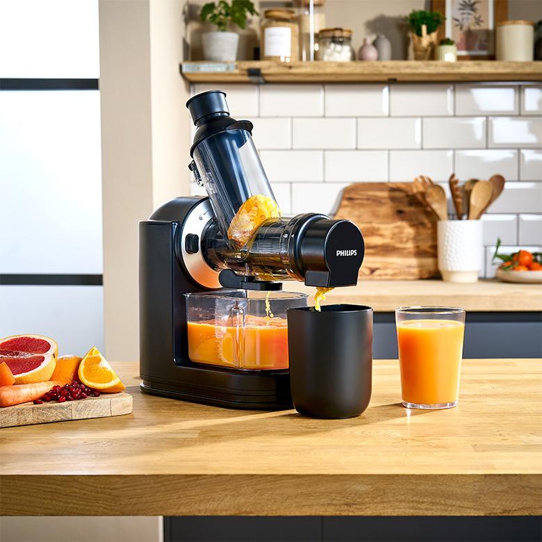 a philips viva collection juicer being used to make orange juice on a counter