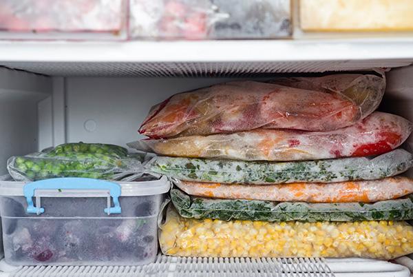 packs of frozen food sitting on a shelf inside an upright freezer
