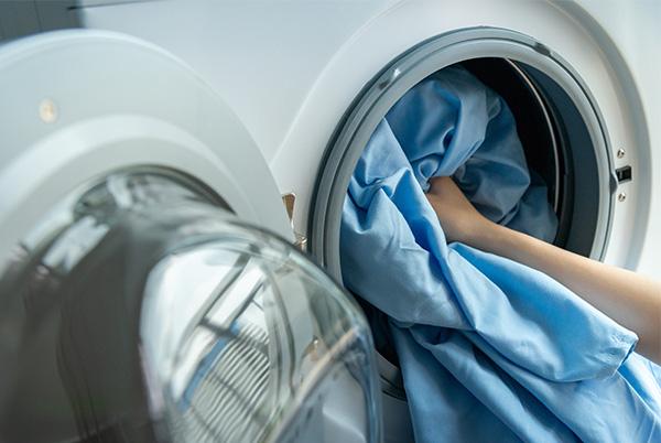 a person taking blue bedsheets out of a washing machine