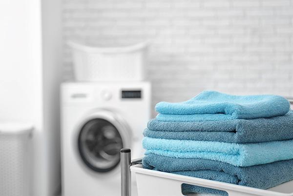 a stack of blue towels on a laundry basket in a laundry room