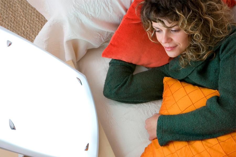 a woman with a towel on her head holding a green light therapy device