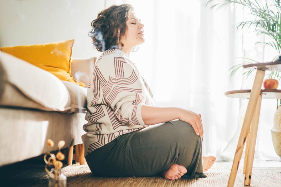a woman sitting in a lotus position on the floor with a laptop
