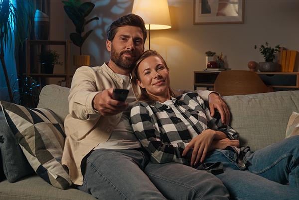 a man and woman sitting on a couch with a remote control