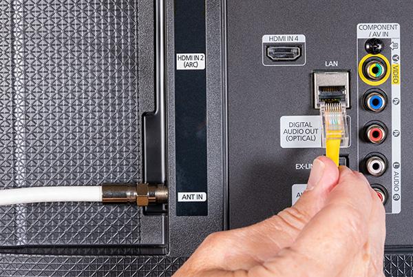 a person is connecting a cable to a device with a yellow cable