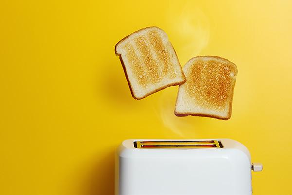 two slices of toast floating in the air over a toaster