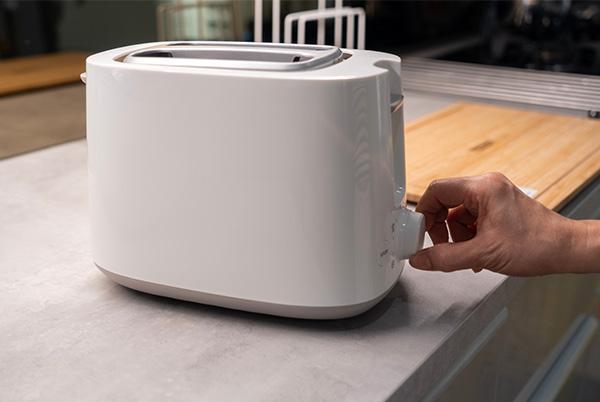a person is twisting the dial on a toaster on a kitchen countertop