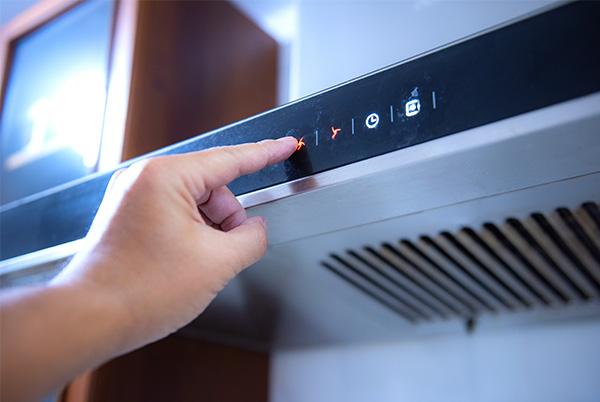 a person pressing a button on a cooker hood