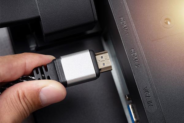 a person holding an hdmi cable in their hand plugging it into a tv