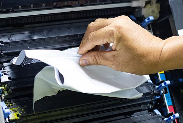 a person pulling jammed paper out of a printer