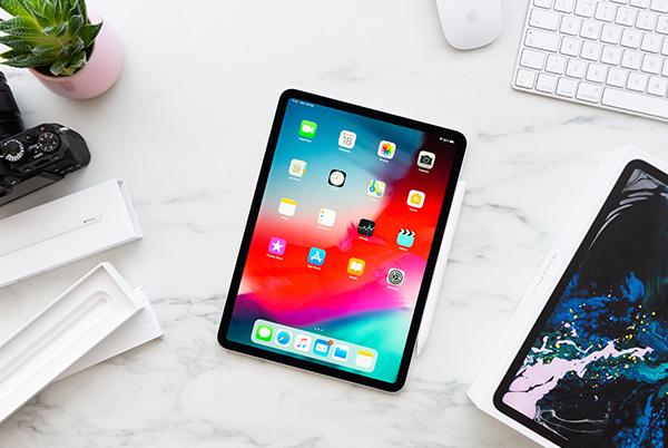 a white marble table with a laptop, ipad, and camera