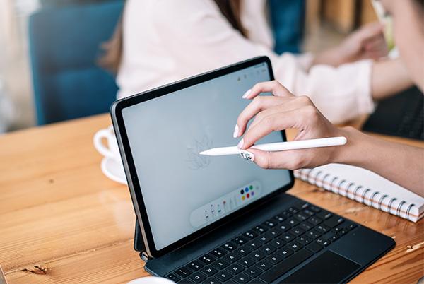 a woman is drawing on a tablet computer with a pen