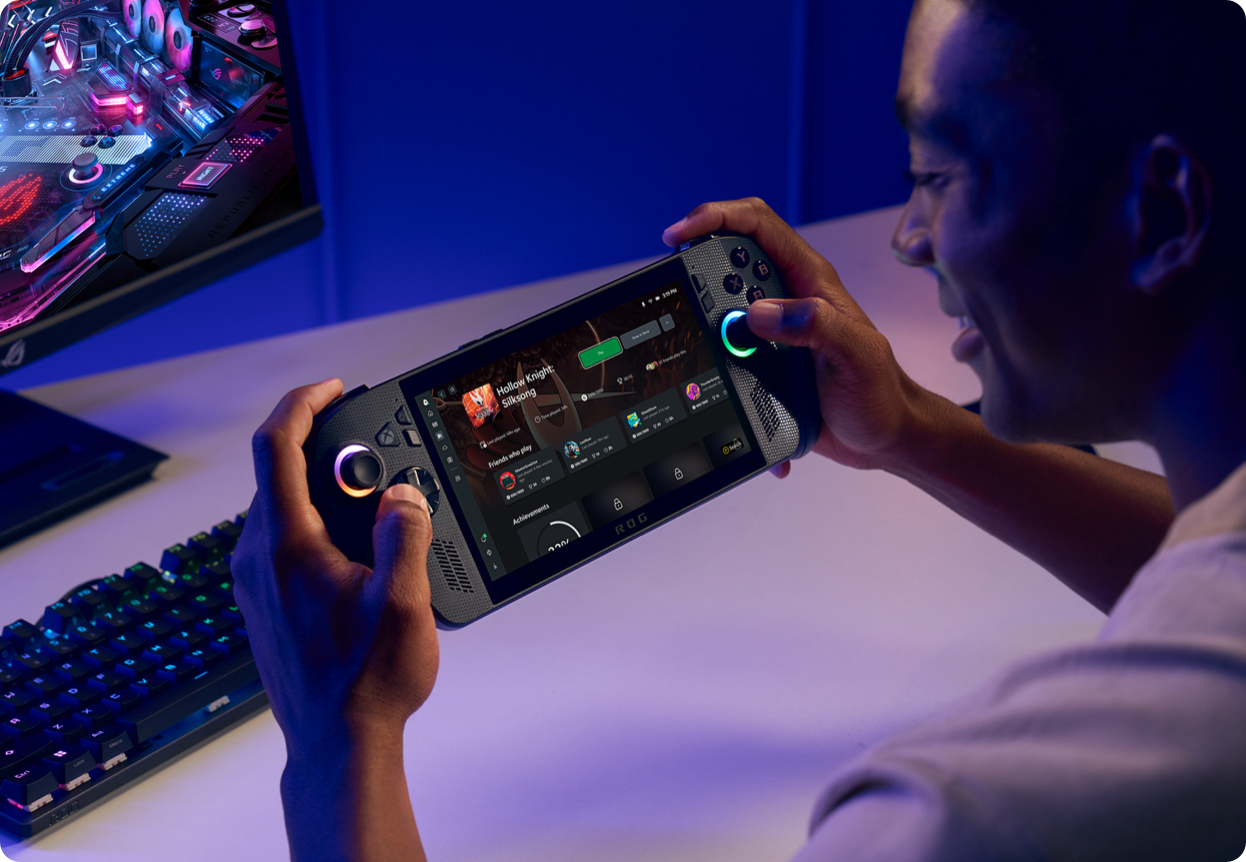 a man holding a game controller in front of a computer monitor