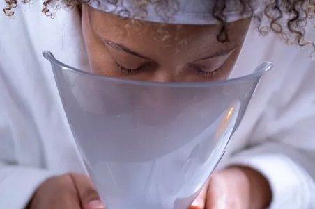a woman with curly hair holding a facial steamer to her face
