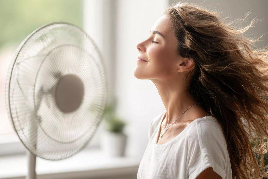 Woman enjoying cool air from pedestal fan