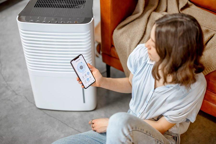 Woman holding a smartphone to controlling a smart dehumidifiers