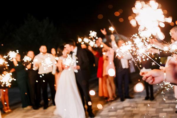 a bride and groom are surrounded by their guests with sparklers