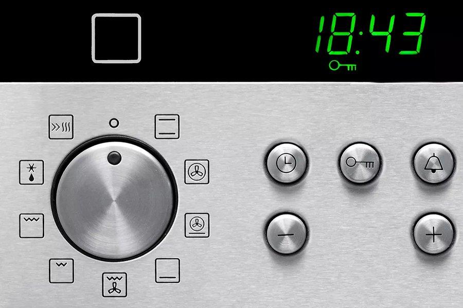 Close-up of the front of an oven showing a dial with symbols around it