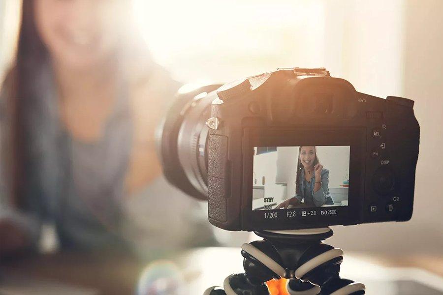 A DSLR camera pointing away, with a smiling woman on the display