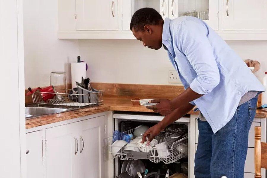 A man loading a dishwasher in a kitchen