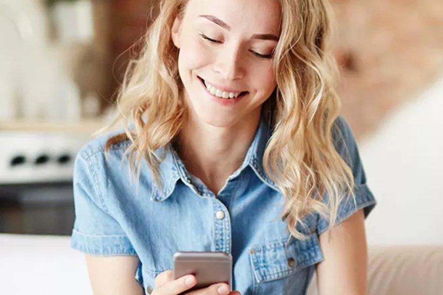A woman smiling and looking down at her phone