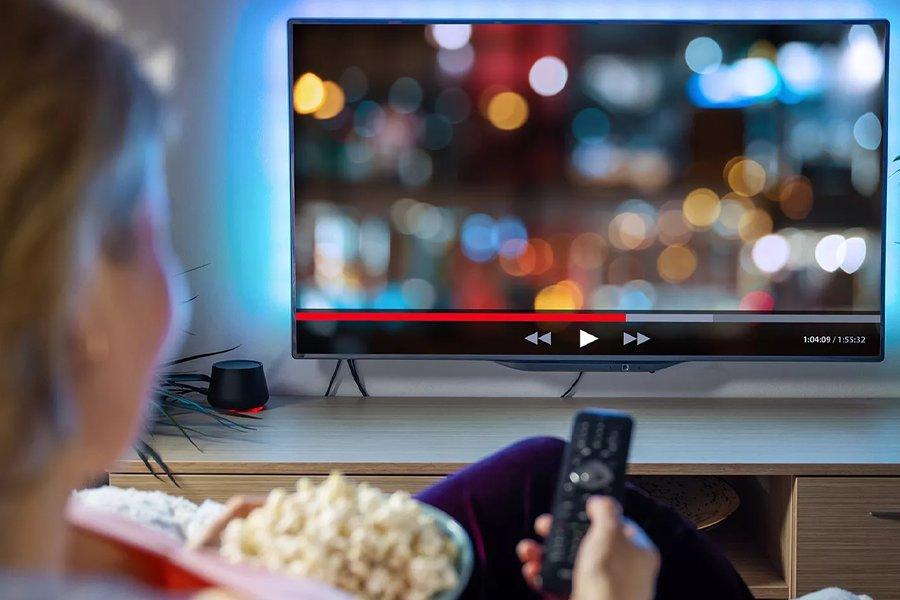 The back of a person holding a remote and looking at a television