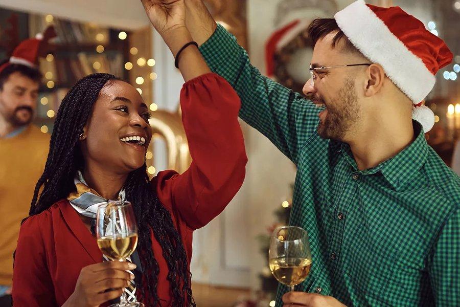 A woman and a man hold hands in the air whilst drinking from champagne flutes
