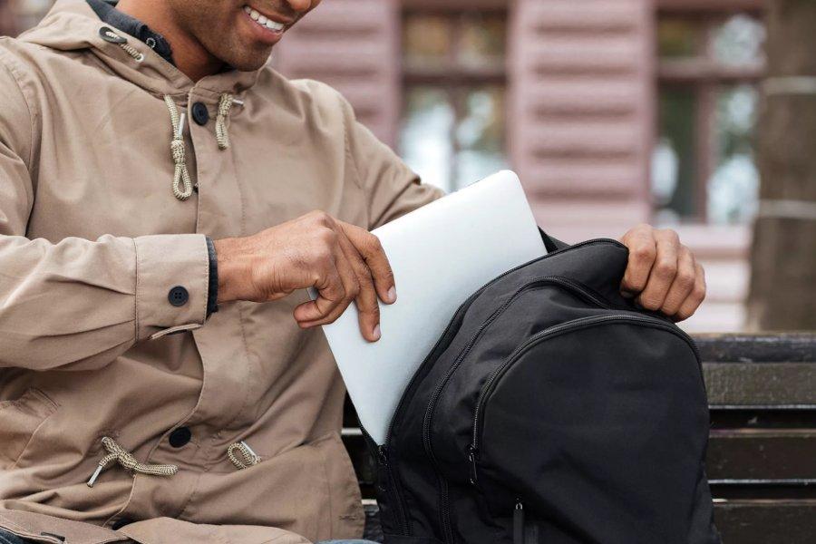A person putting a laptop into a backpack