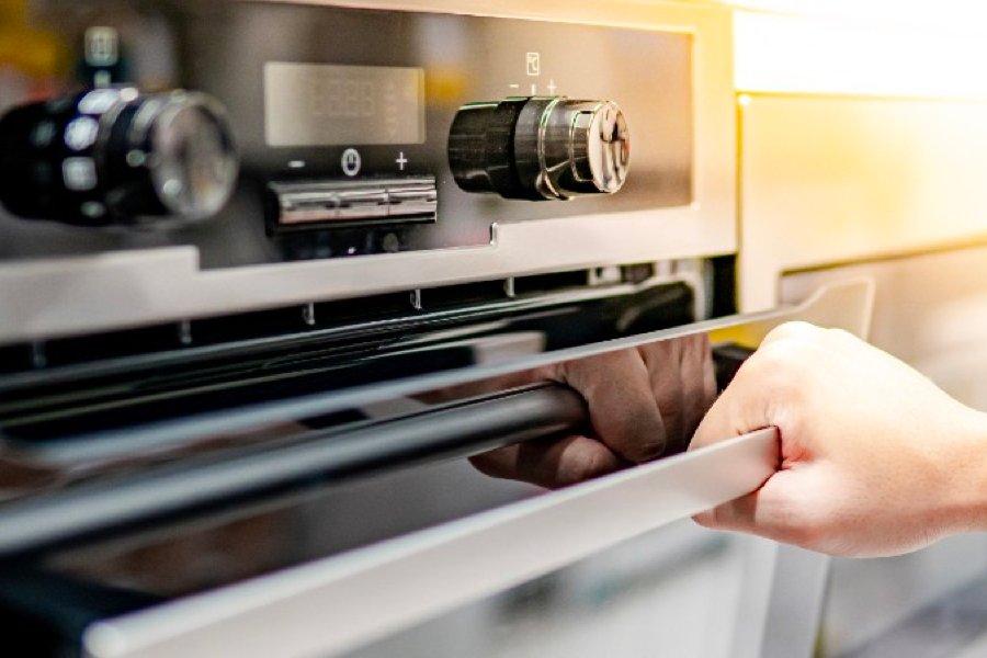 A hand opening an oven door