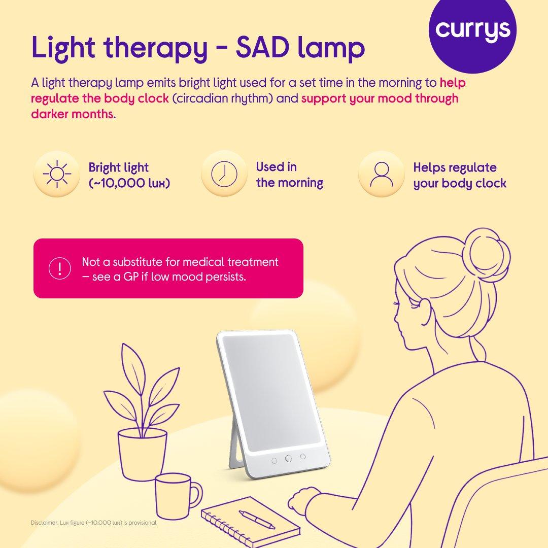 Infographic titled 'Light therapy - SAD lamp', showing an illustration of a person sitting at a desk in front of a light therapy lamp, with a plant, mug and notebook nearby. Text explains that a light therapy lamp emits bright light used for a set time in the morning to help regulate the body clock (circadian rhythm) and support mood through darker months. Three icons highlight bright light (~10,000 lux), use in the morning, and helping regulate the body clock. A note states this is not a substitute for medical treatment and to see a GP if low mood persists, with a disclaimer that the lux figure is provisional.