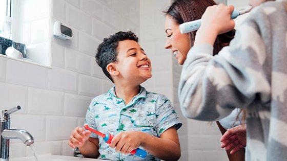 a woman and boy brushing teeth in bathroom together