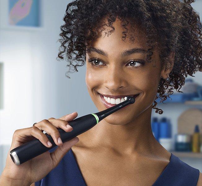 a woman brushing her teeth with an electric toothbrush