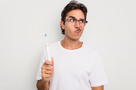 a man in glasses holding a toothbrush in his mouth