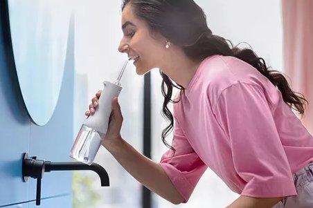 a woman brushing her teeth with a toothbrush in a bathroom