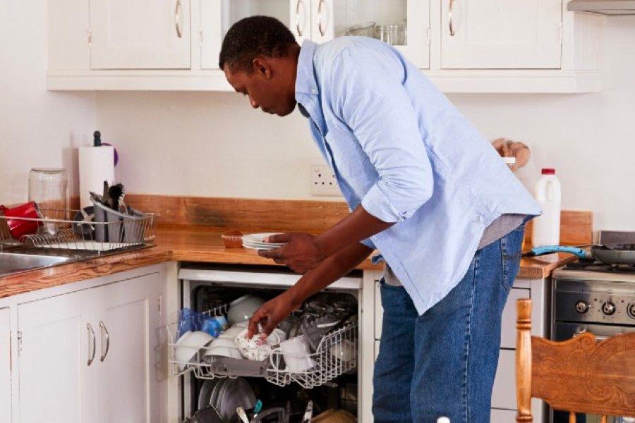 A man putting crockery into a dishwasher in a kitchen