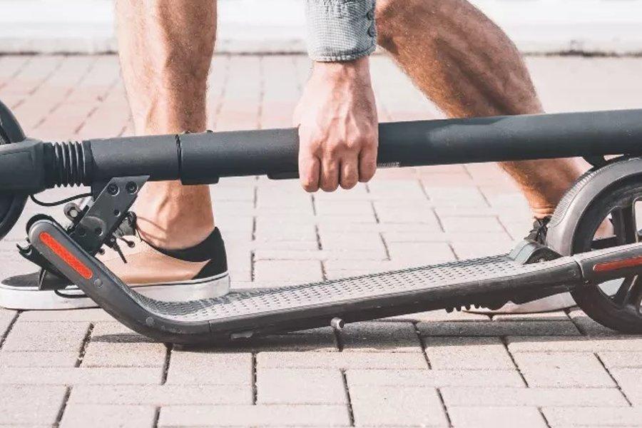 A person picking up a folded electric scooter