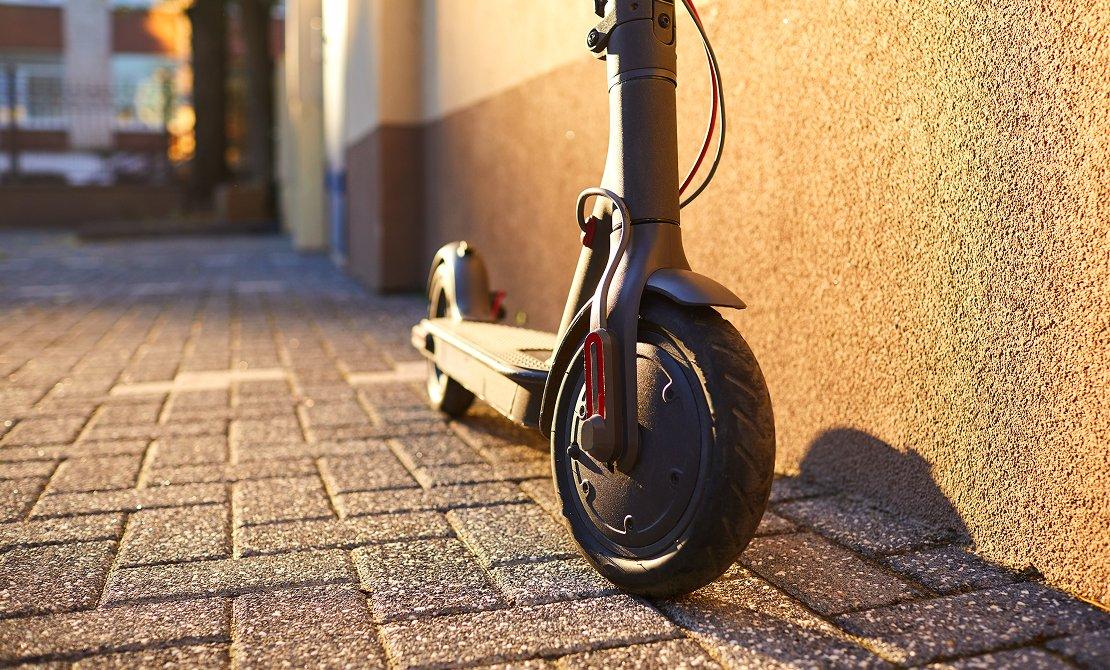 a scooter parked on the side of a brick wall