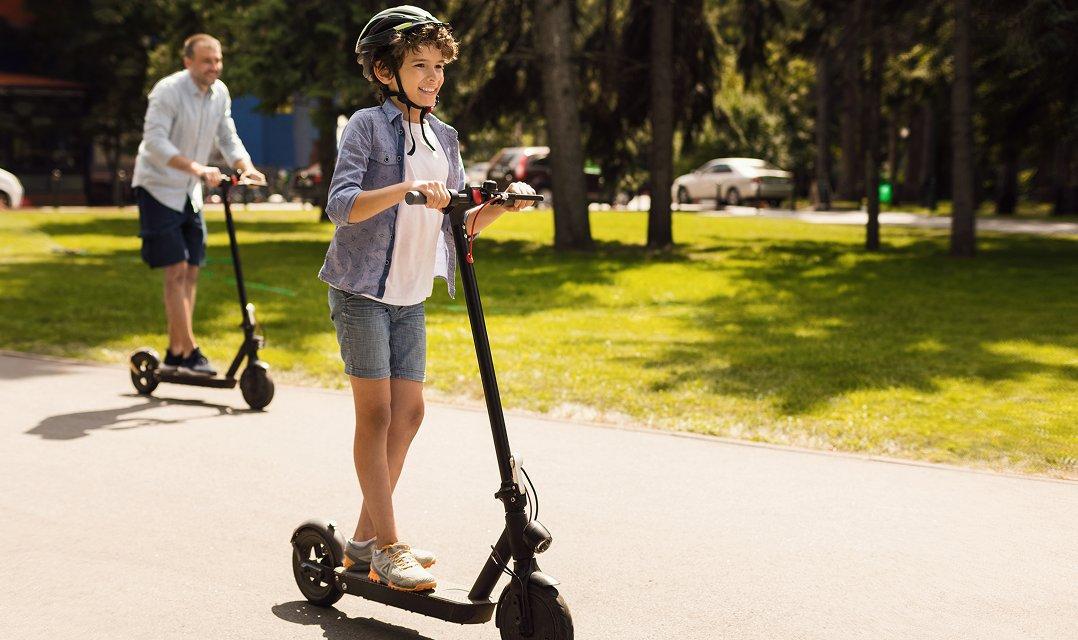 a man and a boy riding electric scooters down a street