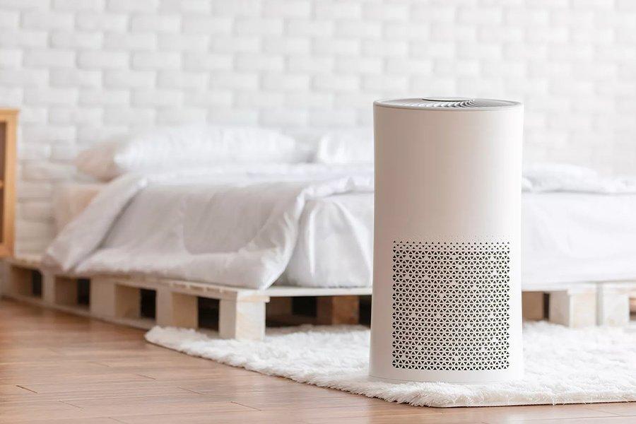 A white appliance on a rug in front of a bed