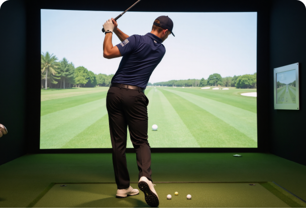 A man swinging a golf club in front of a large screen with a golf course on it