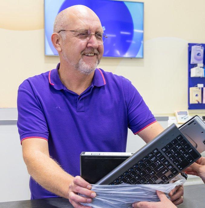 a man in a purple shirt is holding a laptop in a plastic bag
