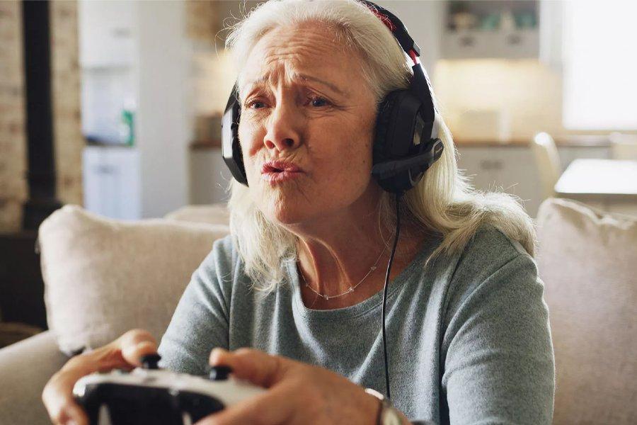 An older woman wearing a headset and holding a gaming controller